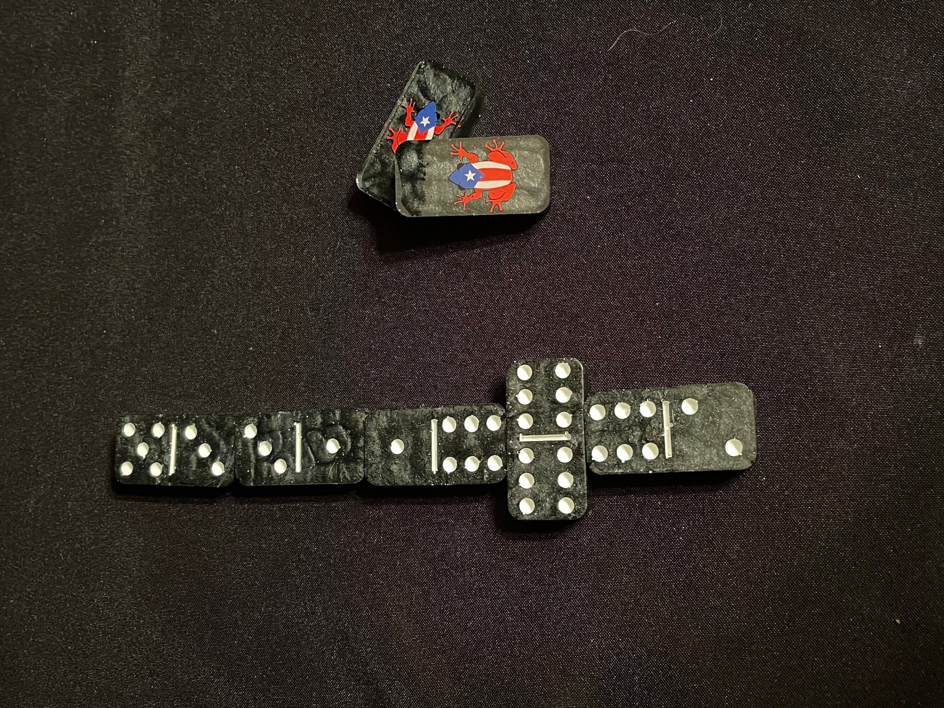 Top down view of the black dominoes with white dots and 2 showing off the design